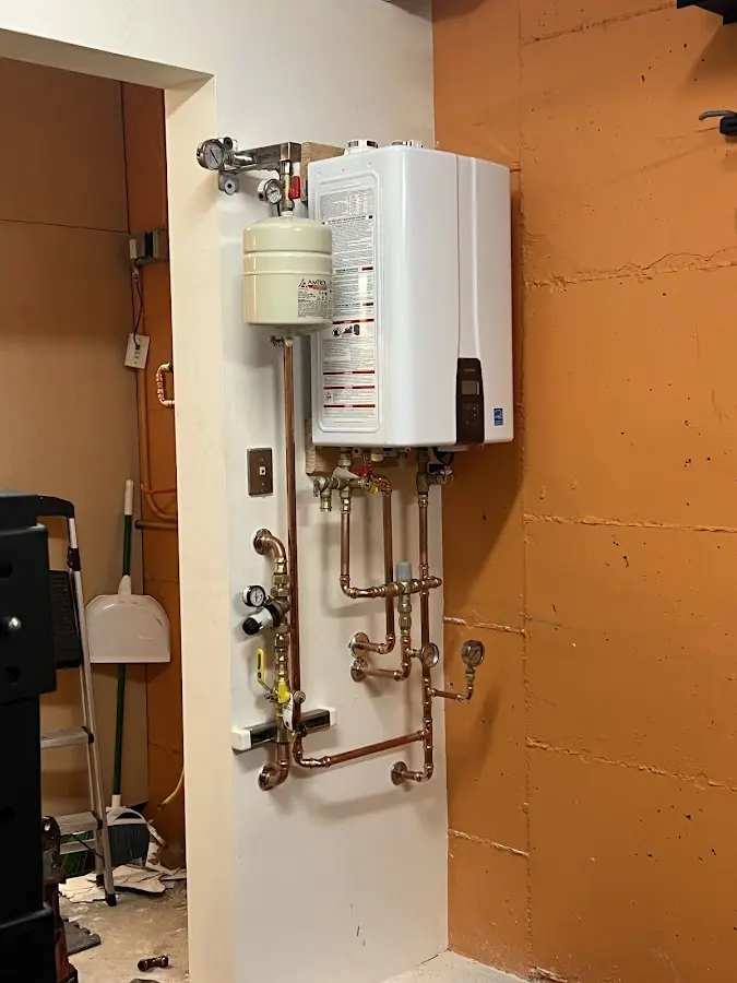Plumbing technician inspecting water heater connections in Long Branch